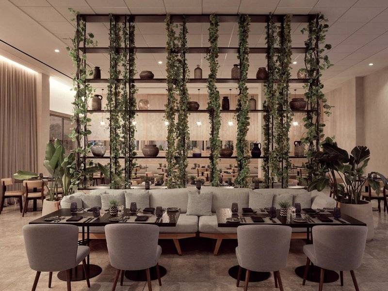 Inneneinrichtung des Mare Paphos Hotels, Restaurantbereich mit grünen Pflanzen und Holztischen.