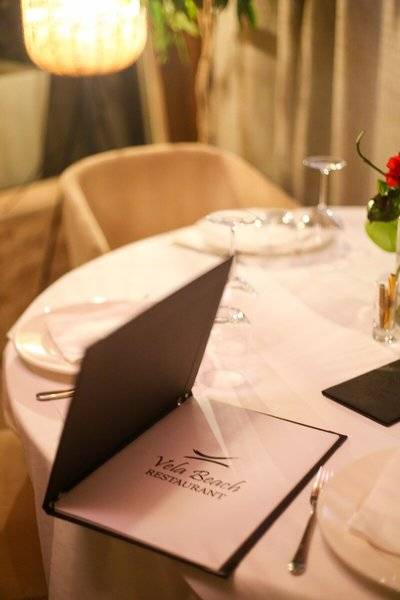 Tisch im Vela Beach Restaurant im Oricon Coast Luxury Resort mit Menü und Geschirr