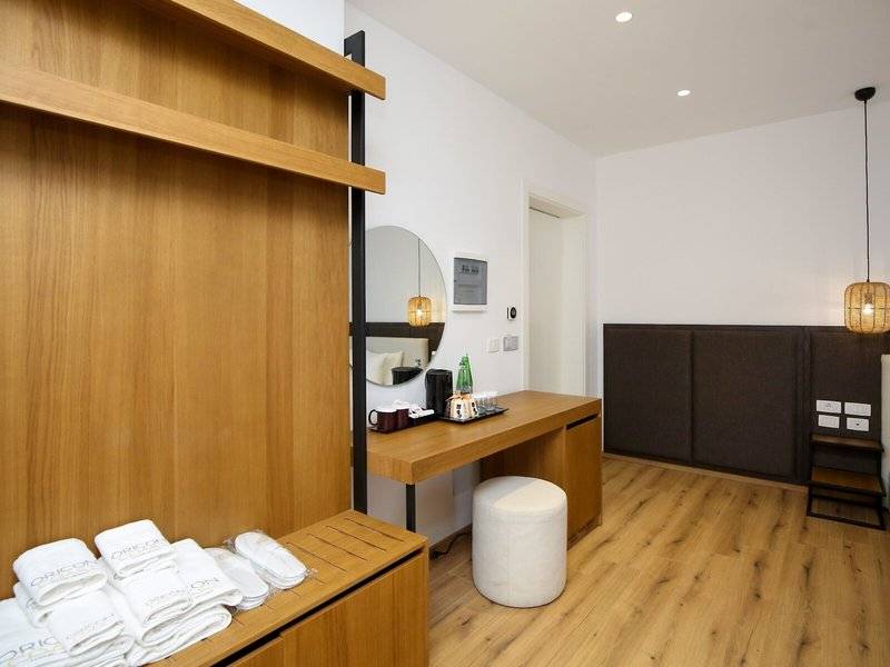 Innenansicht eines eleganten Hotelzimmers mit Holzboden und Möbeln, einem Schreibtisch und einem großen Spiegel.