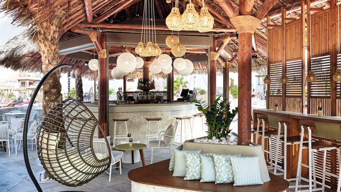 Loungebereich des Atlantica Caldera Palace Hotels mit Hängesessel, Tischen und Bar.