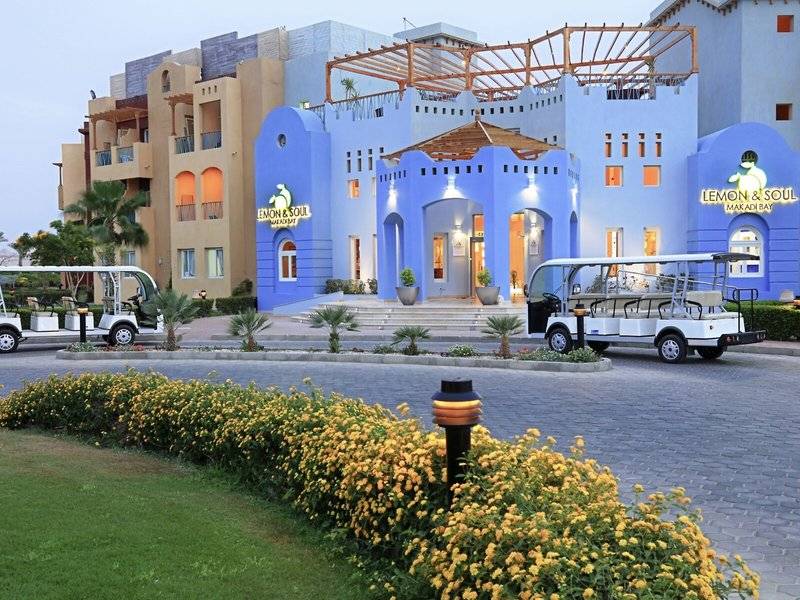 Vorderansicht des Lemon & Soul Garden Makadi Hotels mit zwei Elektrofahrzeugen vor dem Eingang.