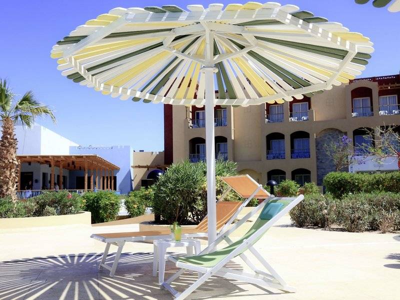 Sonnenschirm und Liegestuhl vor dem Lemon & Soul Garden Makadi Hotel.
