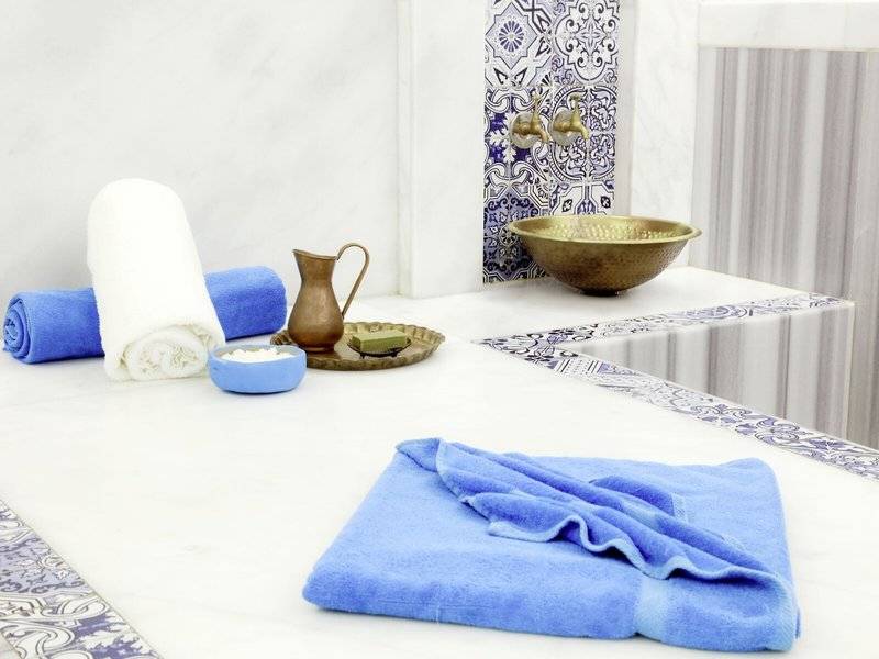 Spa-Bereich im Lemon & Soul Garden Makadi mit weißen und blauen Handtüchern, einem goldenen Becken und anderen Spa-Utensilien.