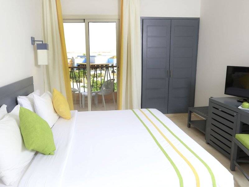 Schlafzimmer mit Balkon im Lemon & Soul Garden Makadi Hotel, ausgestattet mit einem großen Bett, Fernseher und Blick auf Terrasse.