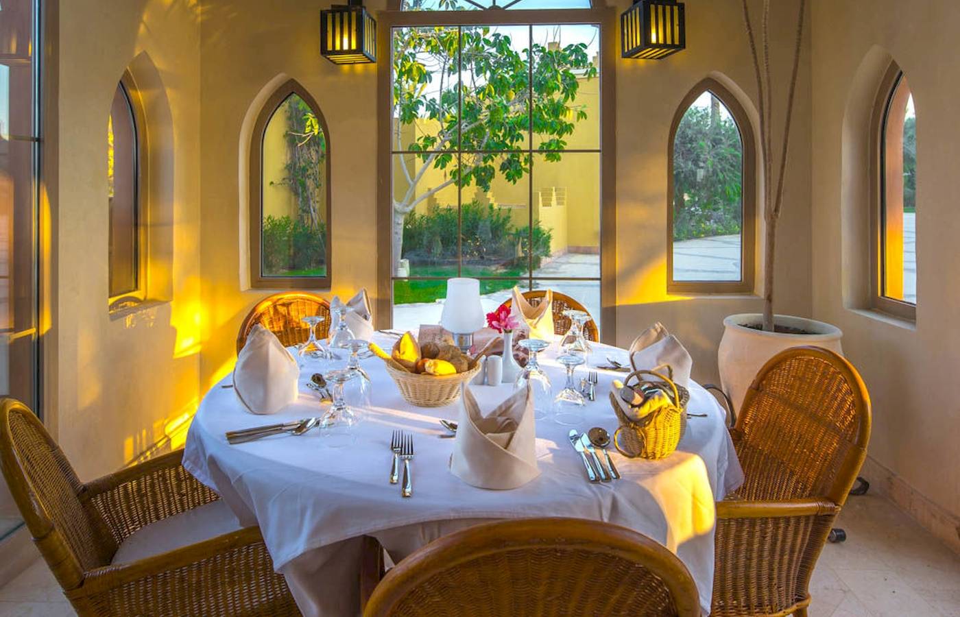Essenbereich im Grand Makadi Hotel mit Tisch, Stühlen und Blick auf einen Garten.