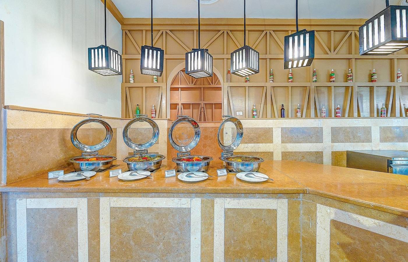 Buffet-Tisch im Grand Makadi Hotel mit Speisen in Metallschüsseln und hängenden Laternen.