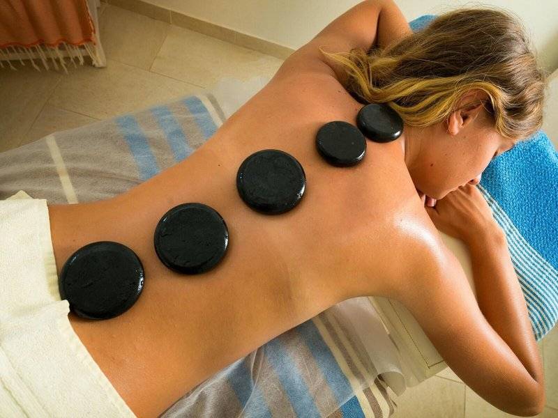 Frau genießt eine Rückenmassage mit schwarzen heißen Steinen im Hotel Iliade Djerba.