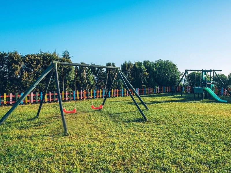 Kinderspielplatz im Hotel Iberostar Waves Averroes mit Schaukeln, Rutsche und buntem Zaun