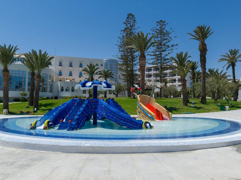 Wasserspielplatz des JAZ Tour Khalef Hotels mit bunten Rutschen vor weißem Gebäude