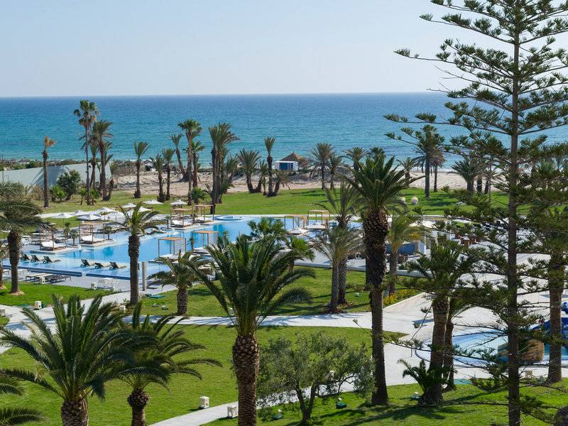 Außenbereich des JAZ Tour Khalef Hotels mit Swimmingpool und Palmen