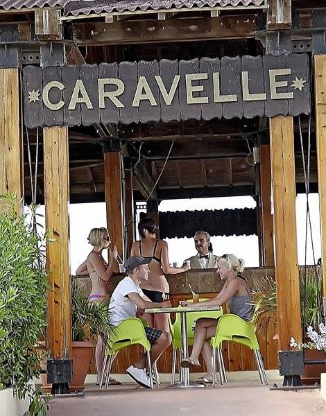 Gäste sitzen in grünen Stühlen vor der Bar Caravella im Sahara Beach AquaPark Resort.