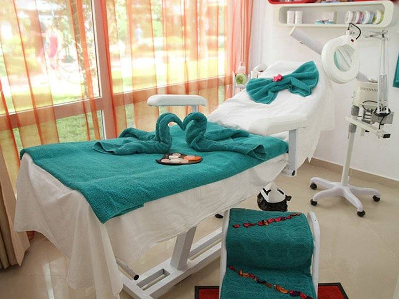 Behandlungszimmer im Sahara Beach AquaPark Resort mit grünen Handtüchern und Blick auf den Garten.