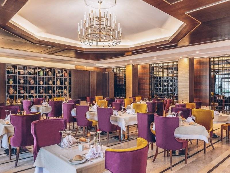Innenbereich des Iberostar Selection Kuriat Palace Hotels mit einem runden Esstisch und einem großen Kronleuchter.