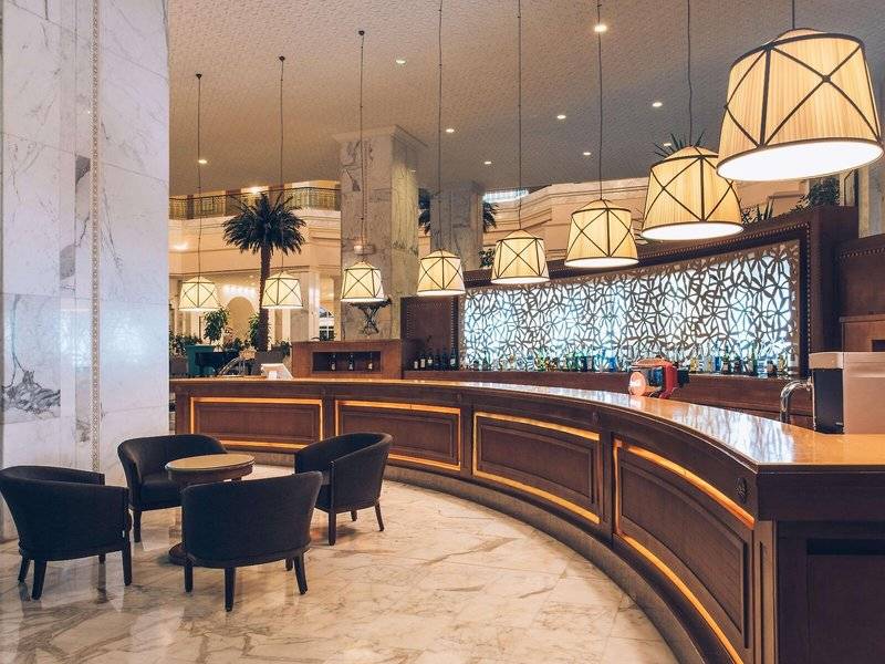 Hotellobby des Iberostar Selection Kantaoui Bay mit Bar, Sesseln und Kronleuchtern.