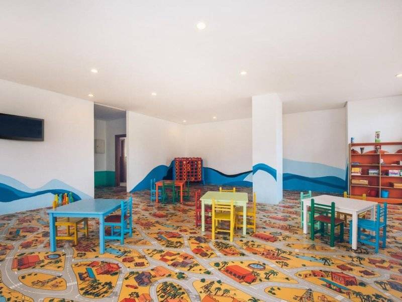 Kinderspielzimmer im Iberostar Selection Kantaoui Bay mit bunten Tischen, Stühlen und Wandmalerei.