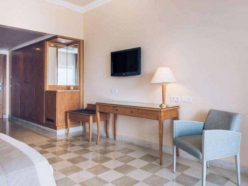 Innenansicht eines Hotelzimmers von Iberostar Selection Kantaoui Bay mit Bett, Schreibtisch, Stuhl und Fernseher.