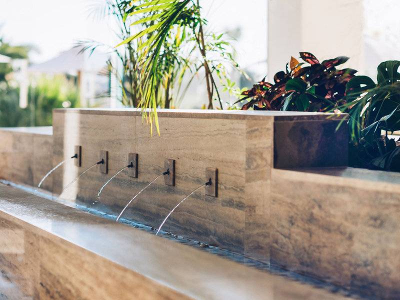 Brunnen im Iberostar Selection Diar El Andalous Hotel mit Wasser und Pflanzen im Hintergrund.