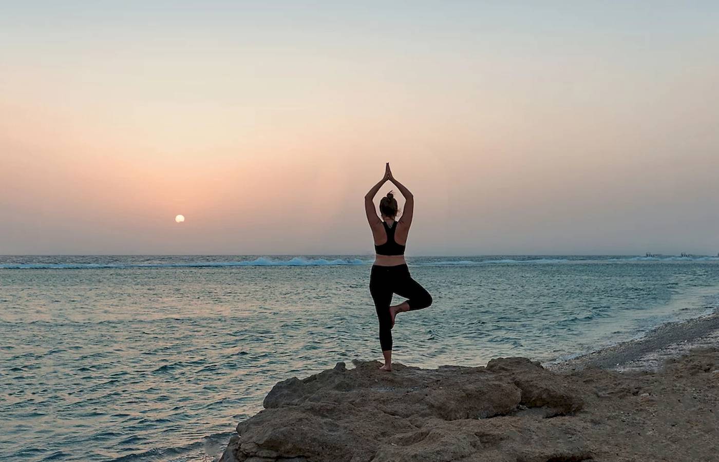 Frau macht Yoga am Strand des Mövenpick Resorts El Quseir.