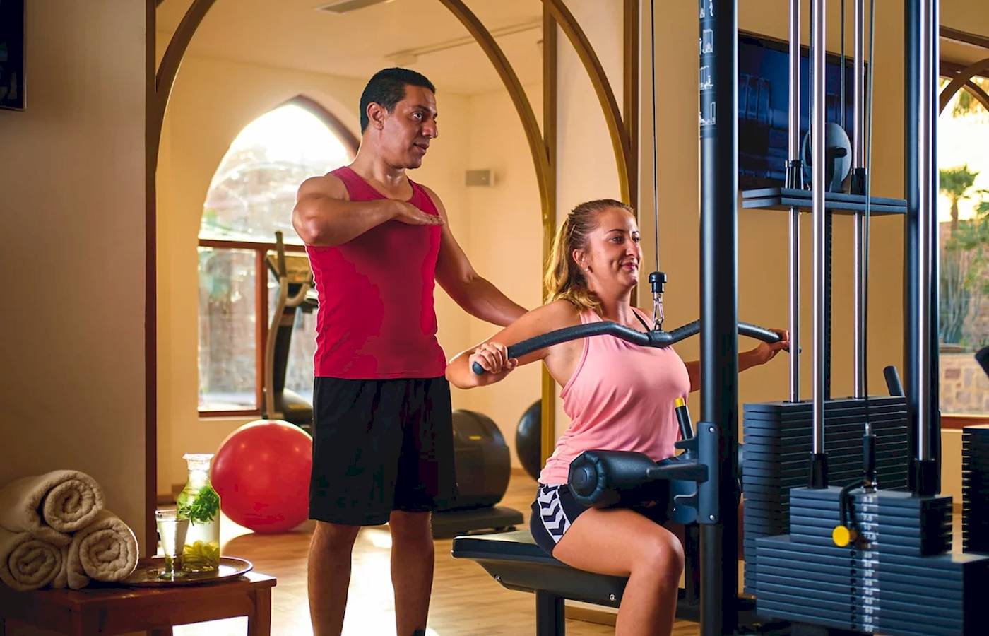 Ein Fitnesstrainer hilft einer Frau im Gym, die ein Trainingsgerät benutzt.