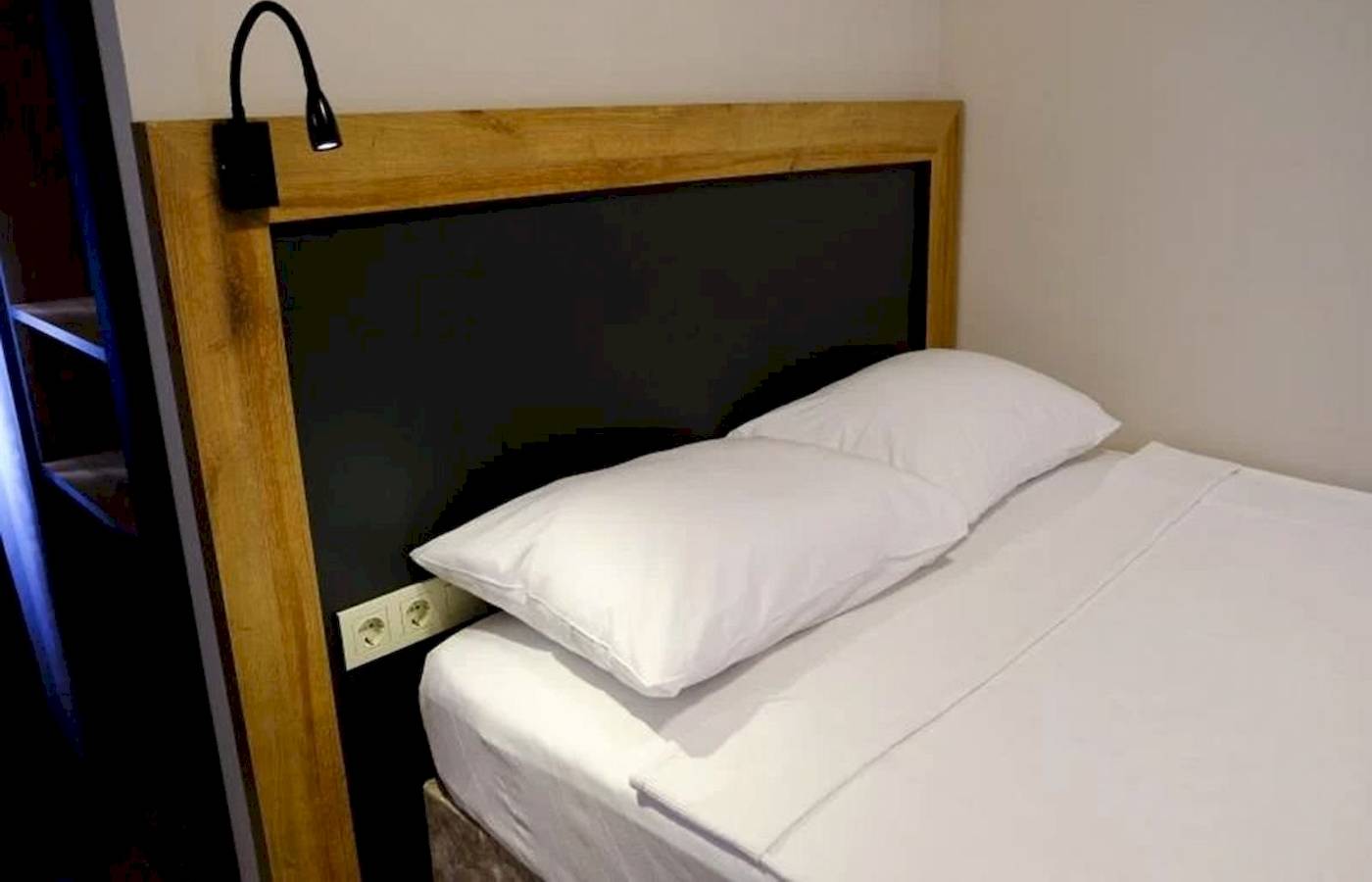 Bett im Club Wasa Holiday Village Hotel mit zwei weißen Kissen und Kopfteilbeleuchtung.