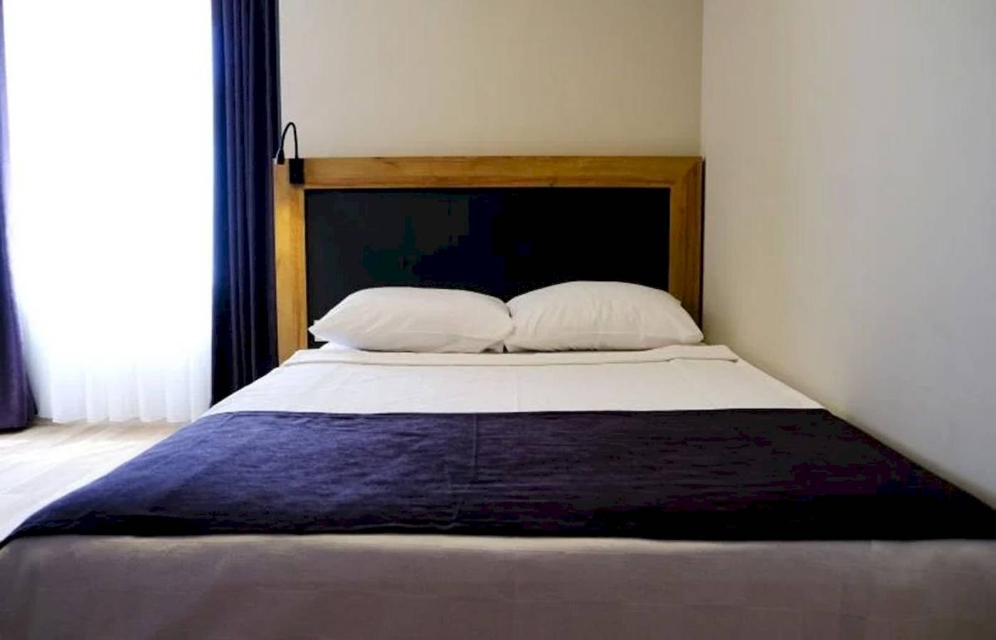 Doppelbett im Schlafzimmer des Club Wasa Holiday Village mit zwei weißen Kissen und blauer Decke.
