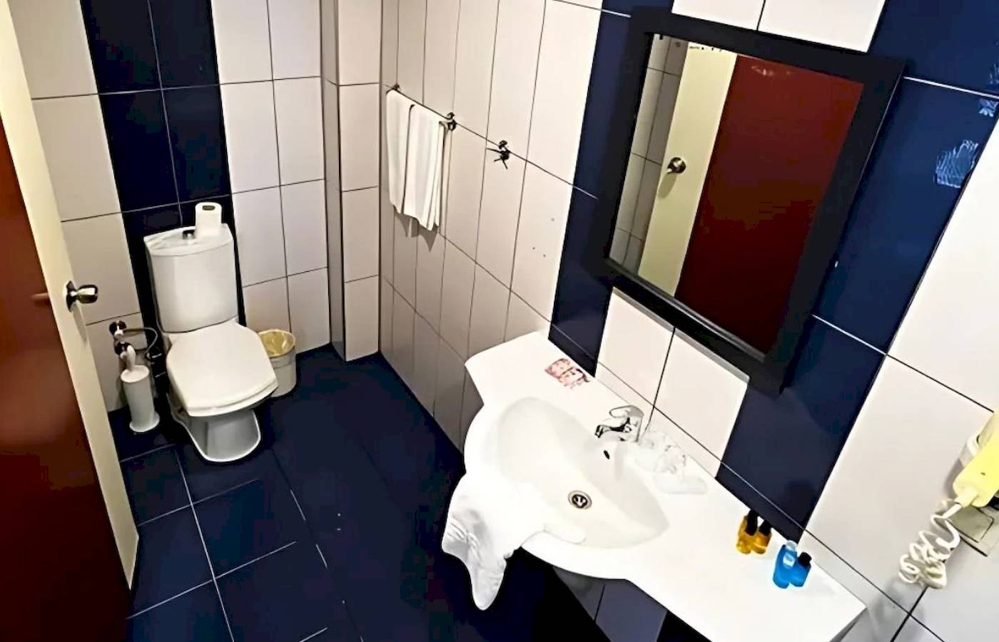 Badezimmer im Club Wasa Holiday Village mit weißer Toilette und blauen Fliesen.