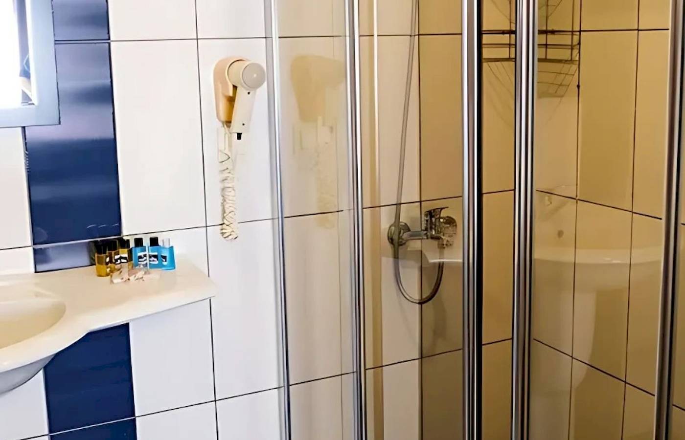 Badezimmer im Club Wasa Holiday Village mit Dusche, Waschbecken und Föhn