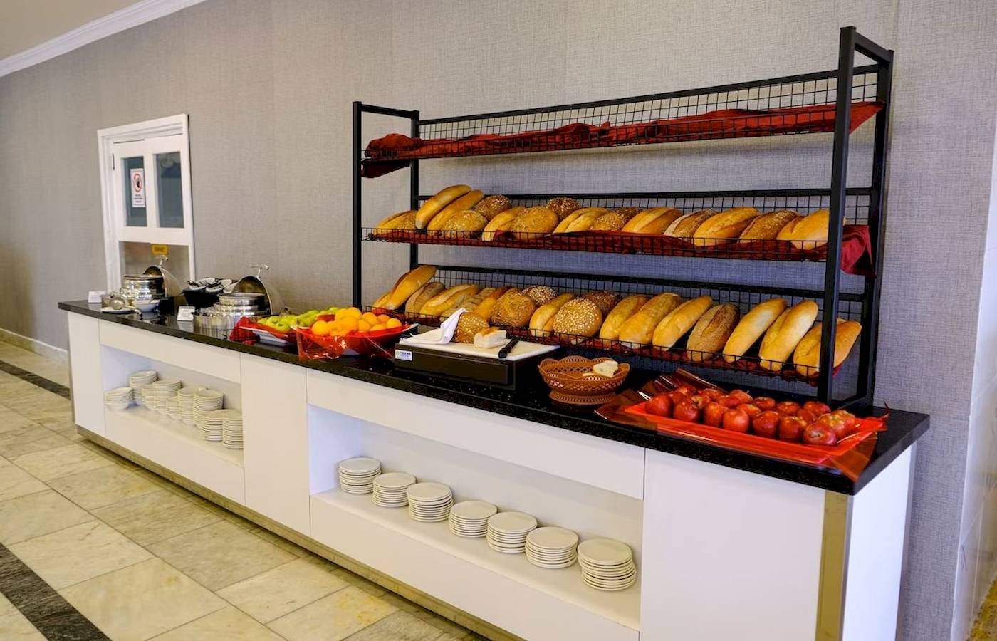Frühstücksbuffet im Club Wasa Holiday Village mit Brot, Obst und Tomaten.