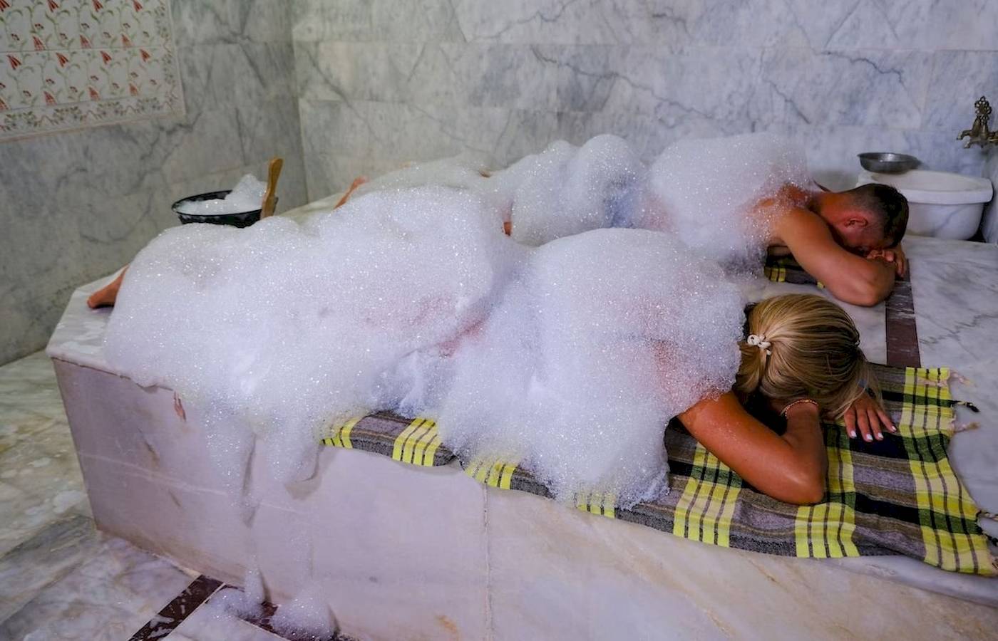 Paar im Club Wasa Holiday Village genießt ein Schaumbad in einer Marmorbadewanne.