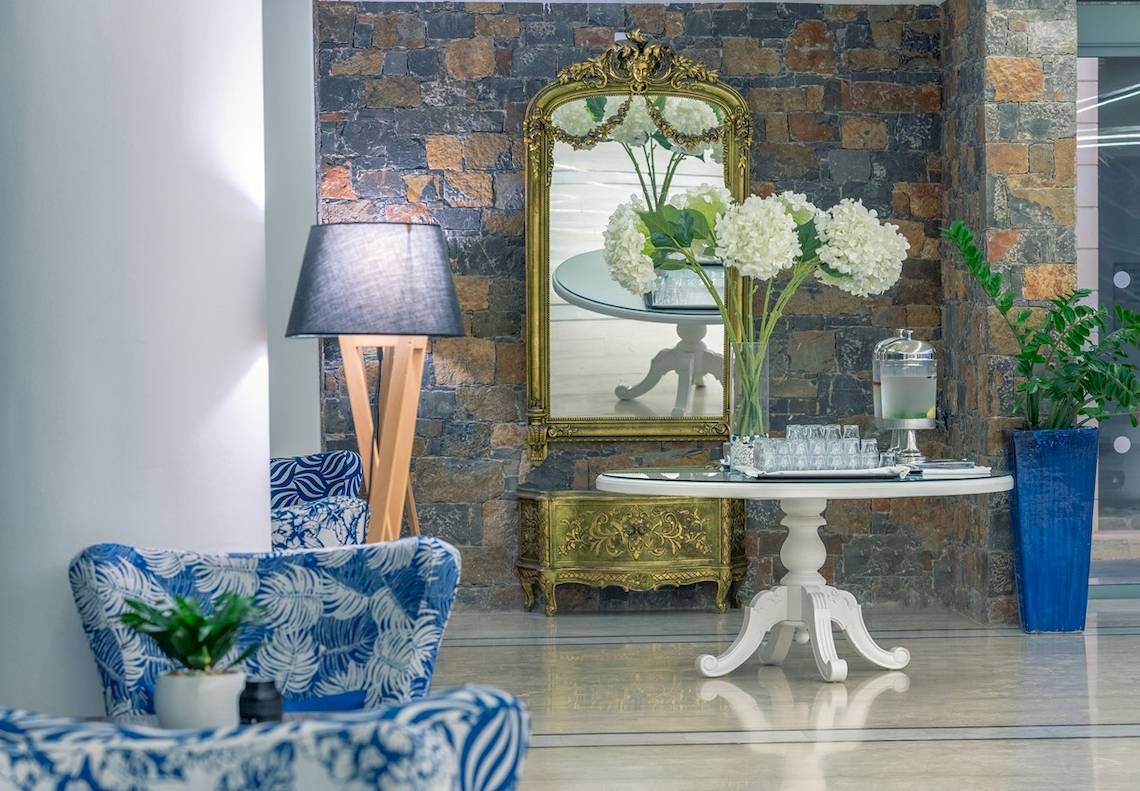 Lobby des Arina Beach Resorts mit Steinwand, Spiegel, Tisch, Blumen und Lampen.