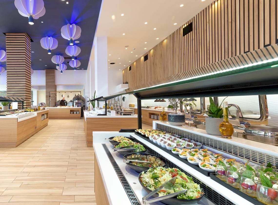 Innenraum des Arina Beach Resorts mit Buffet-Tisch, Holzboden und Beleuchtung.