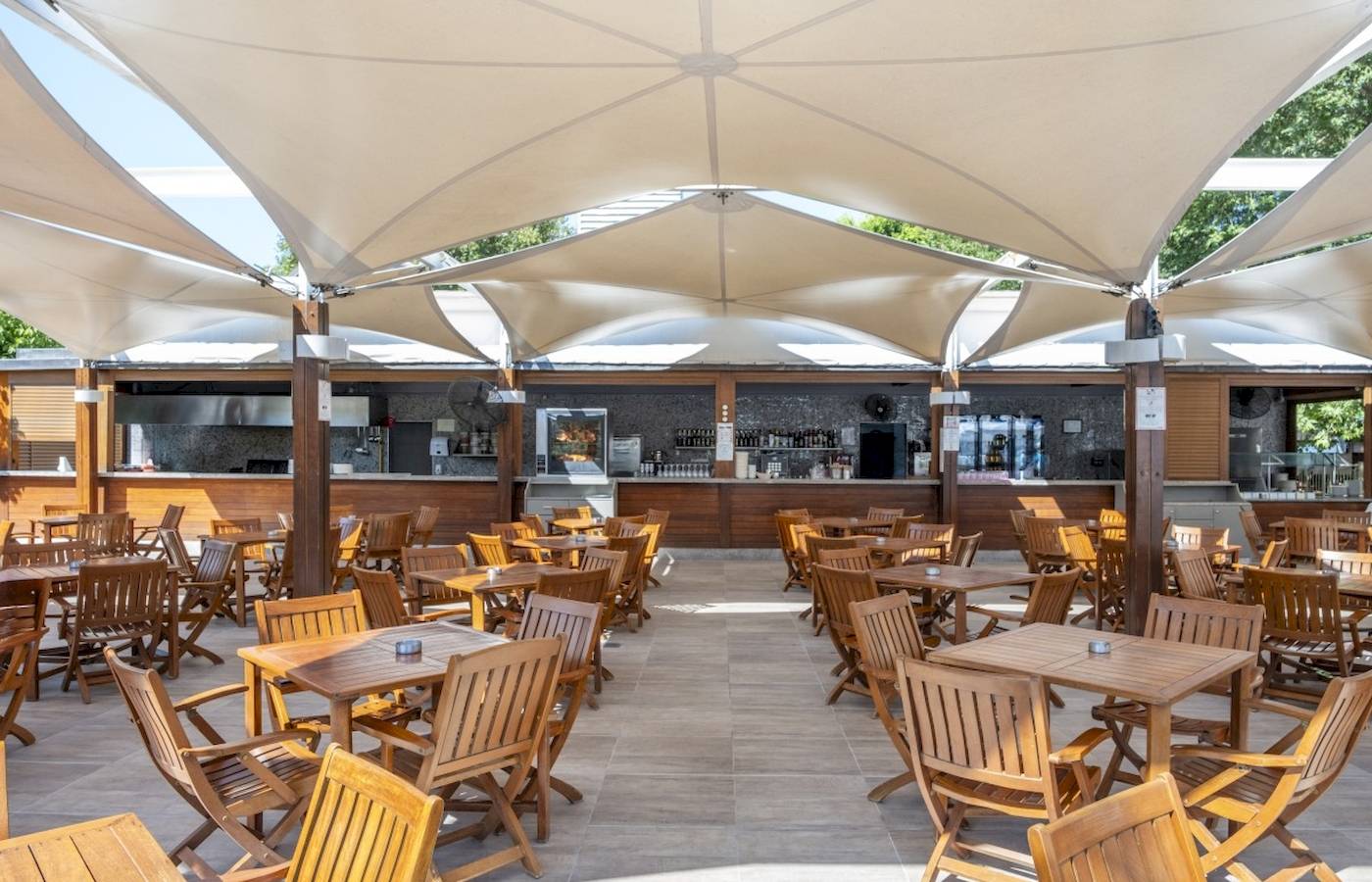 Terrasse des Side Star Elegance Hotels mit vielen Holztischen und Stühlen unter großen Sonnensegeln.