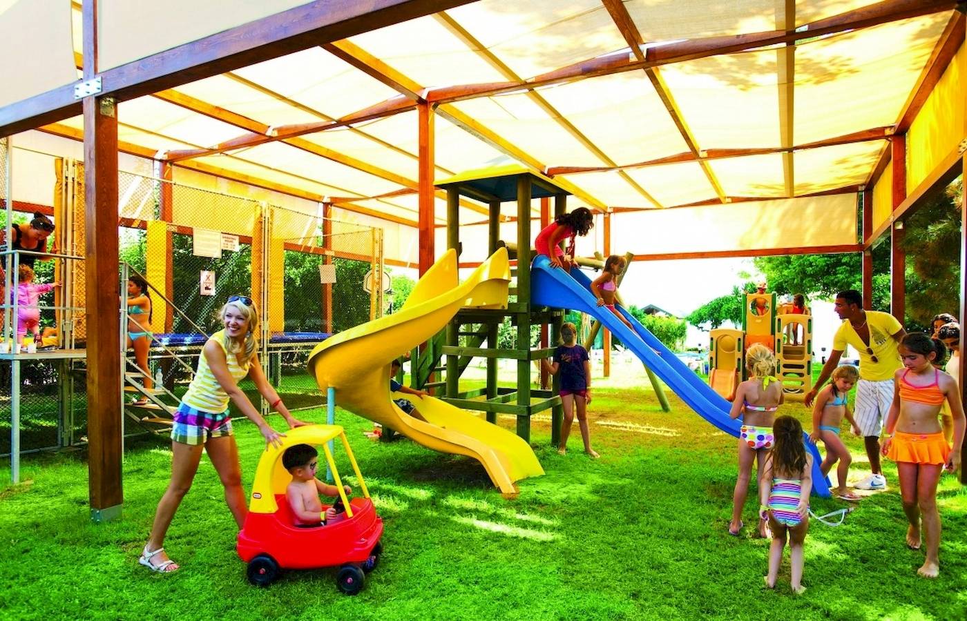 Kinder spielen auf einem Spielplatz im Freien im Hotel Side Star Elegance, mit Rutschen und einem Auto.