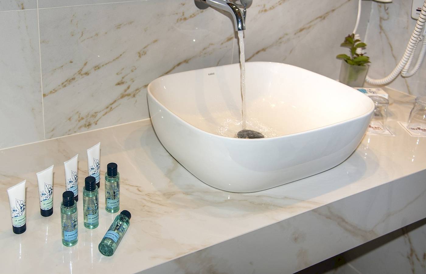 Waschbecken im Badezimmer des Vantaris Luxury Beach Resorts mit Wasserhahn und Pflegeprodukten.