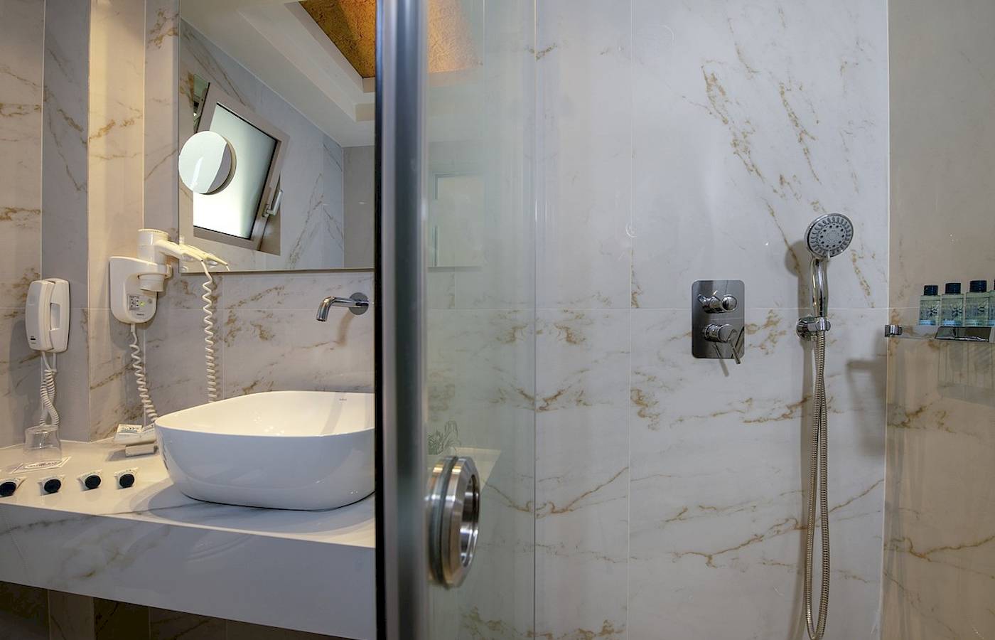 Badezimmer im Vantaris Luxury Beach Resort mit weißem Waschbecken und Marmorwänden.