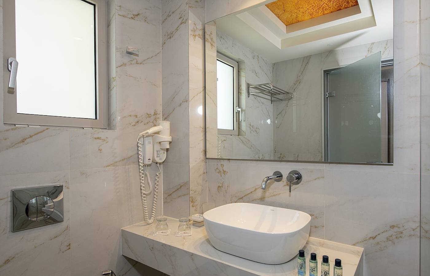 Luxuriöses Badezimmer des Vantaris Luxury Beach Resort mit Marmorfliesen und einer großen Glastür.