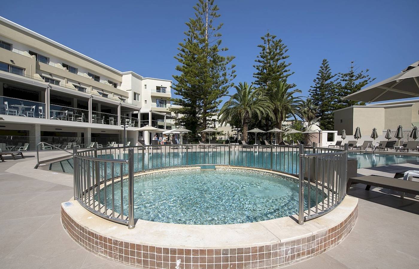 Außenbereich des Vantaris Luxury Beach Resort mit Pool, Sonnenliegen und Schirmen.