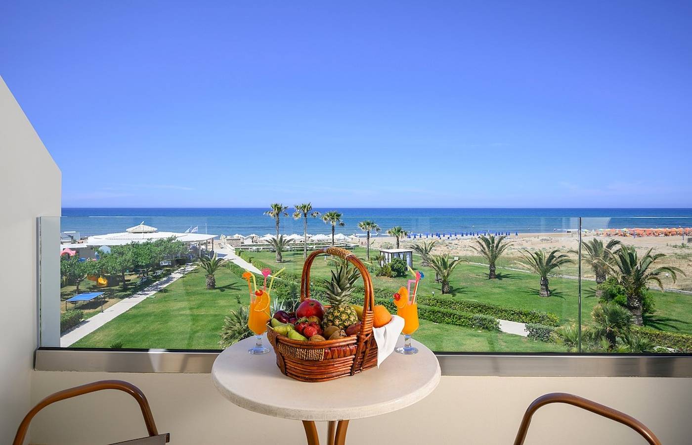 Blick aus dem Hotelfenster auf einen Strand und ein Meer mit einer Glaswand.