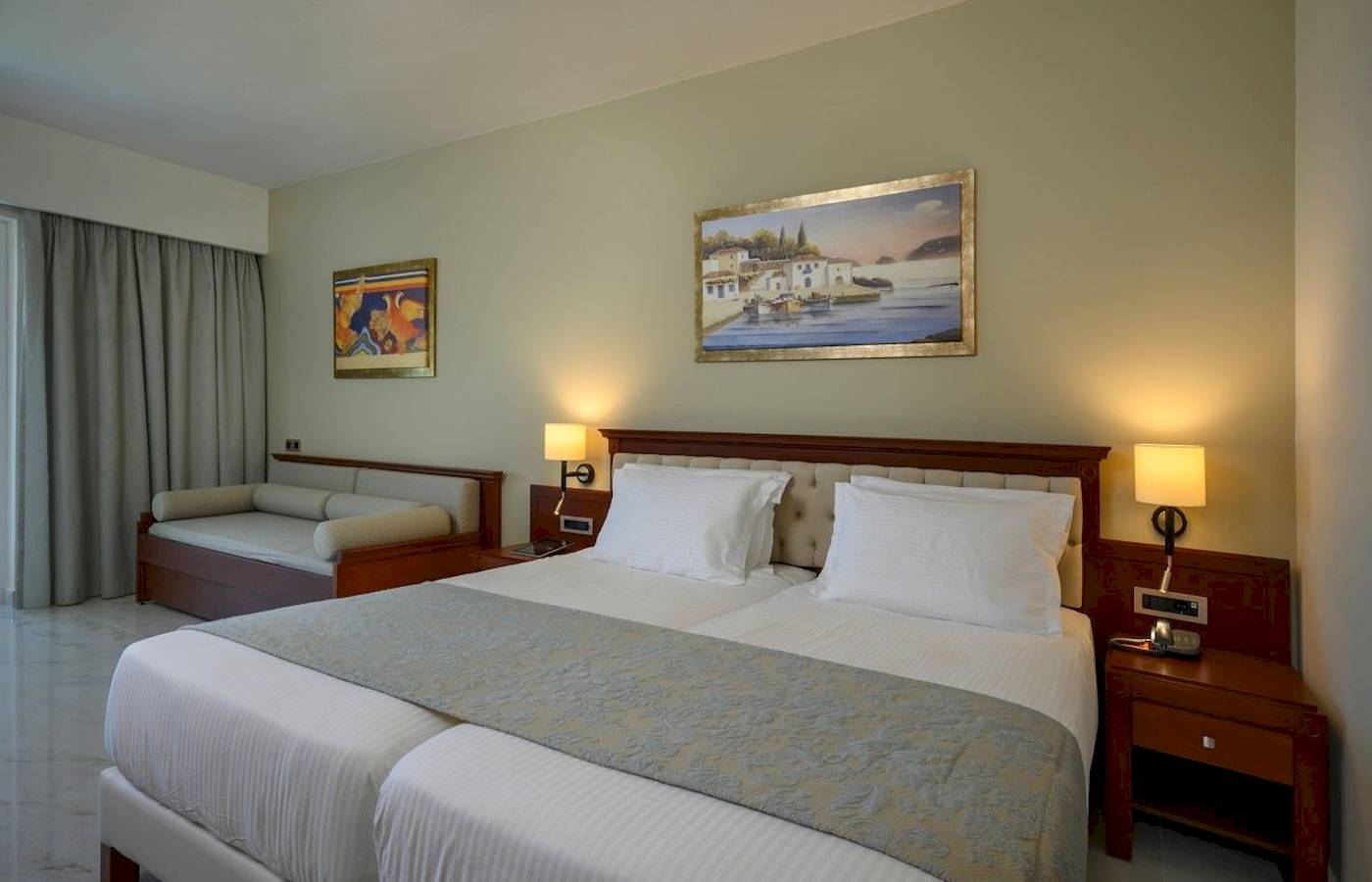 Doppelbett-Zimmer im Vantaris Palace Hotel mit gerahmten Gemälden an der Wand.