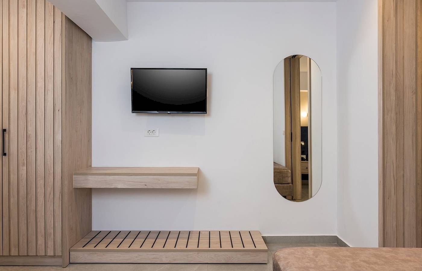Innenansicht eines Zimmers im Vantaris Palace Hotel mit einer Wand, einem Fernseher und einem Spiegel.