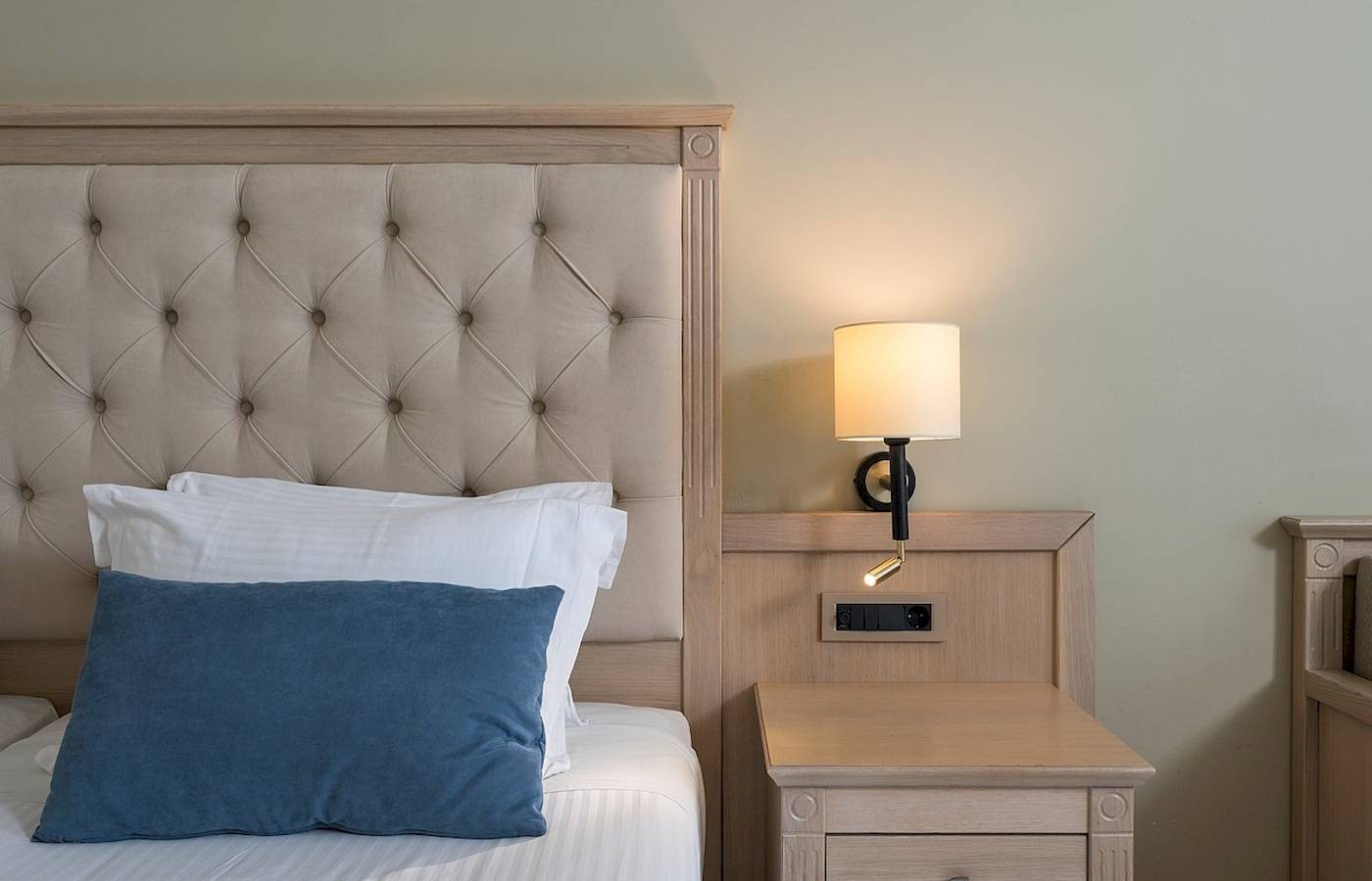 Bett im Vantaris Palace Hotel mit Kissen und Nachttisch neben dem Bett