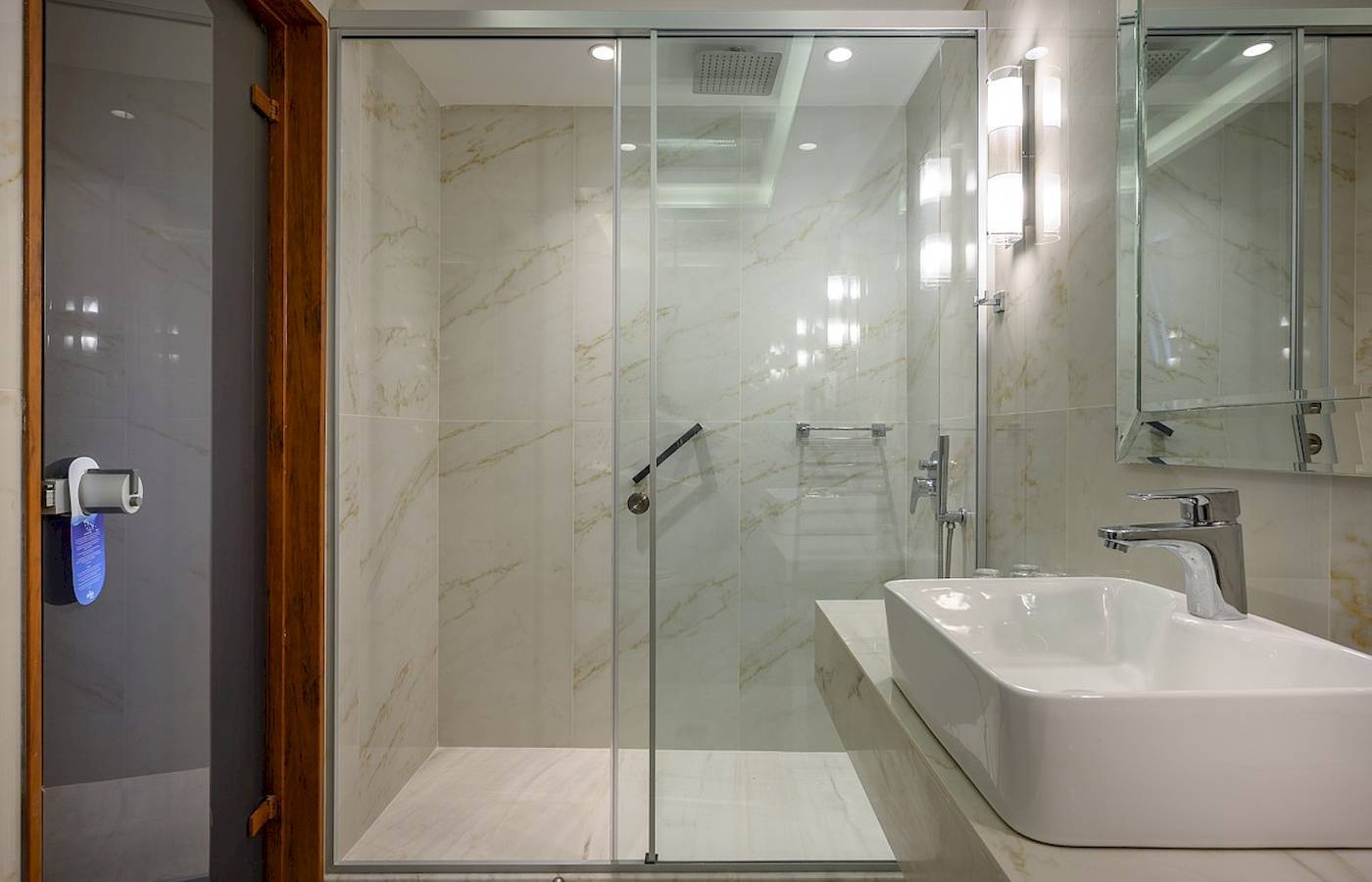 Badezimmer im Vantaris Palace mit einer Glasdusche und einem Waschbecken.