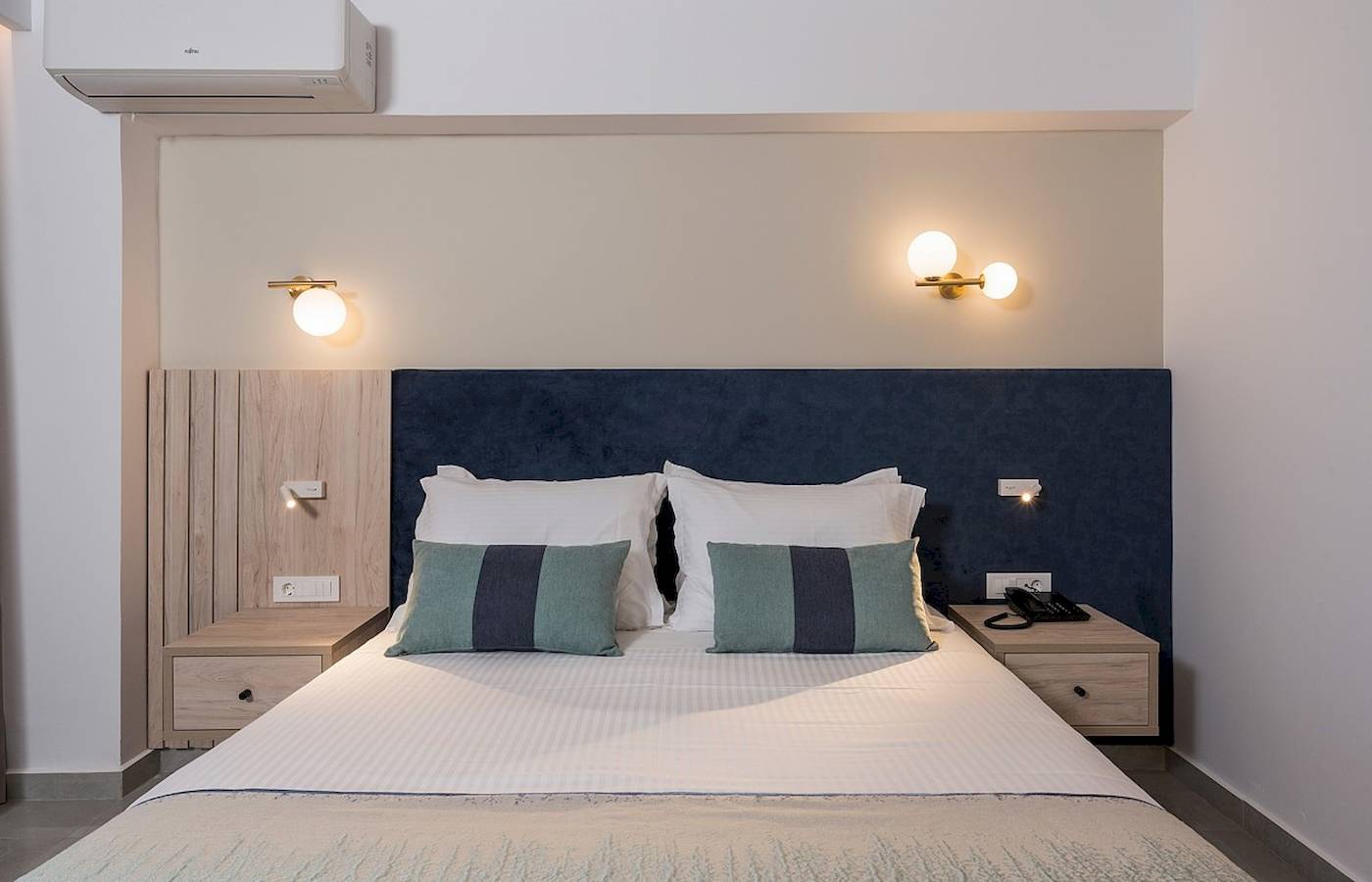 Hotelzimmer im Vantaris Palace mit Bett, Kopfteil, Nachttischen und Klimaanlage