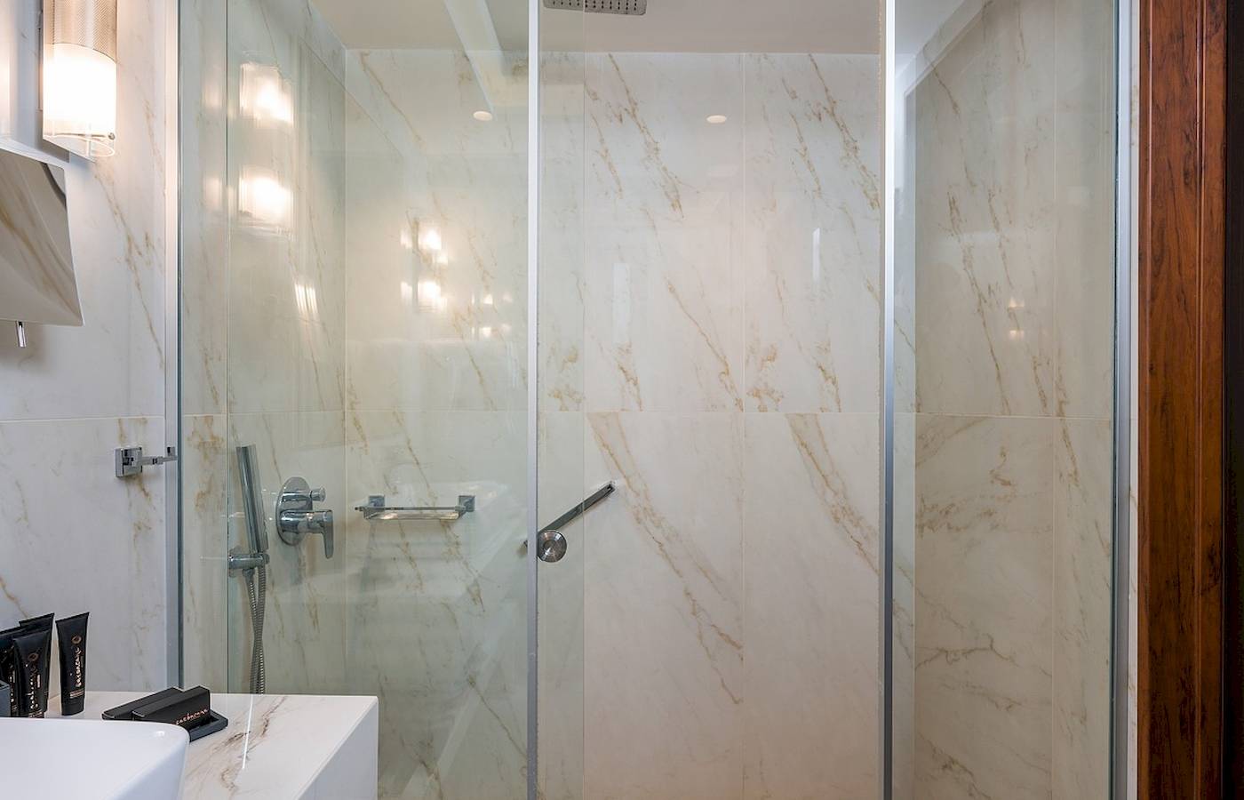 Vantaris Palace Badezimmer mit einer großen Glasdusche und Marmorwänden.