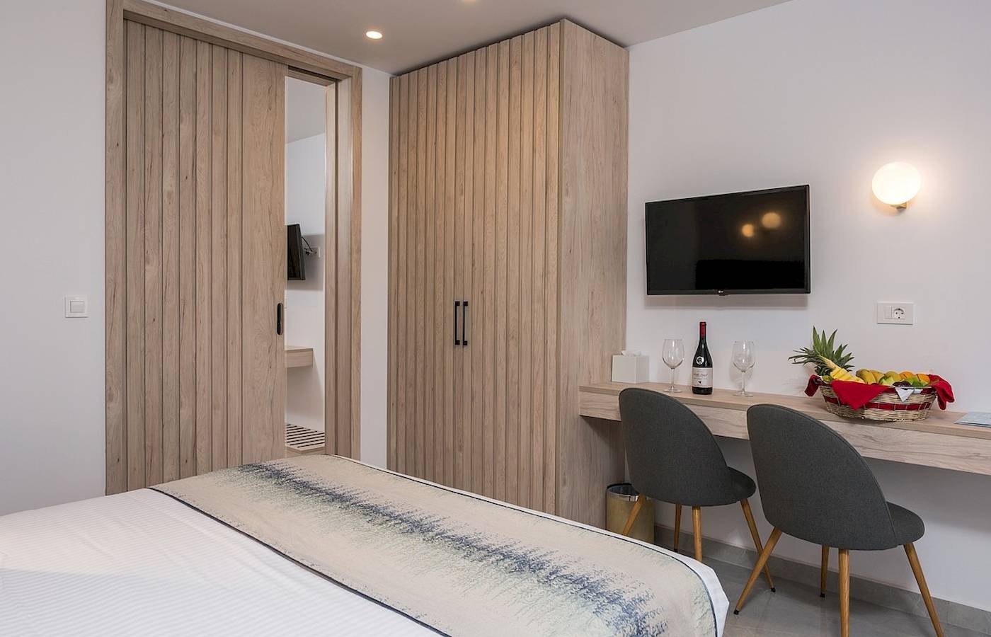 Innenansicht eines Zimmers im Vantaris Palace Hotel mit Bett, Schreibtisch und Fernseher.