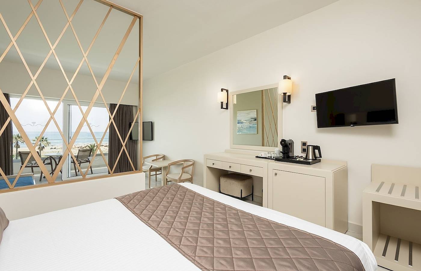 Hotelzimmer mit Meerblick im Vantaris Palace mit einem großen Bett, einem Schreibtisch und einem Fernseher an der Wand.
