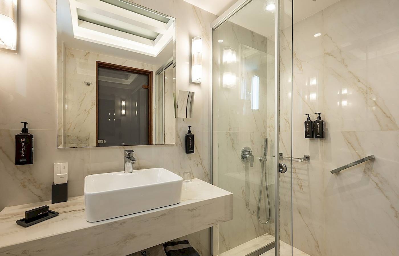 Badezimmer im Vantaris Palace Hotel mit weißer Marmorwand und Dusche