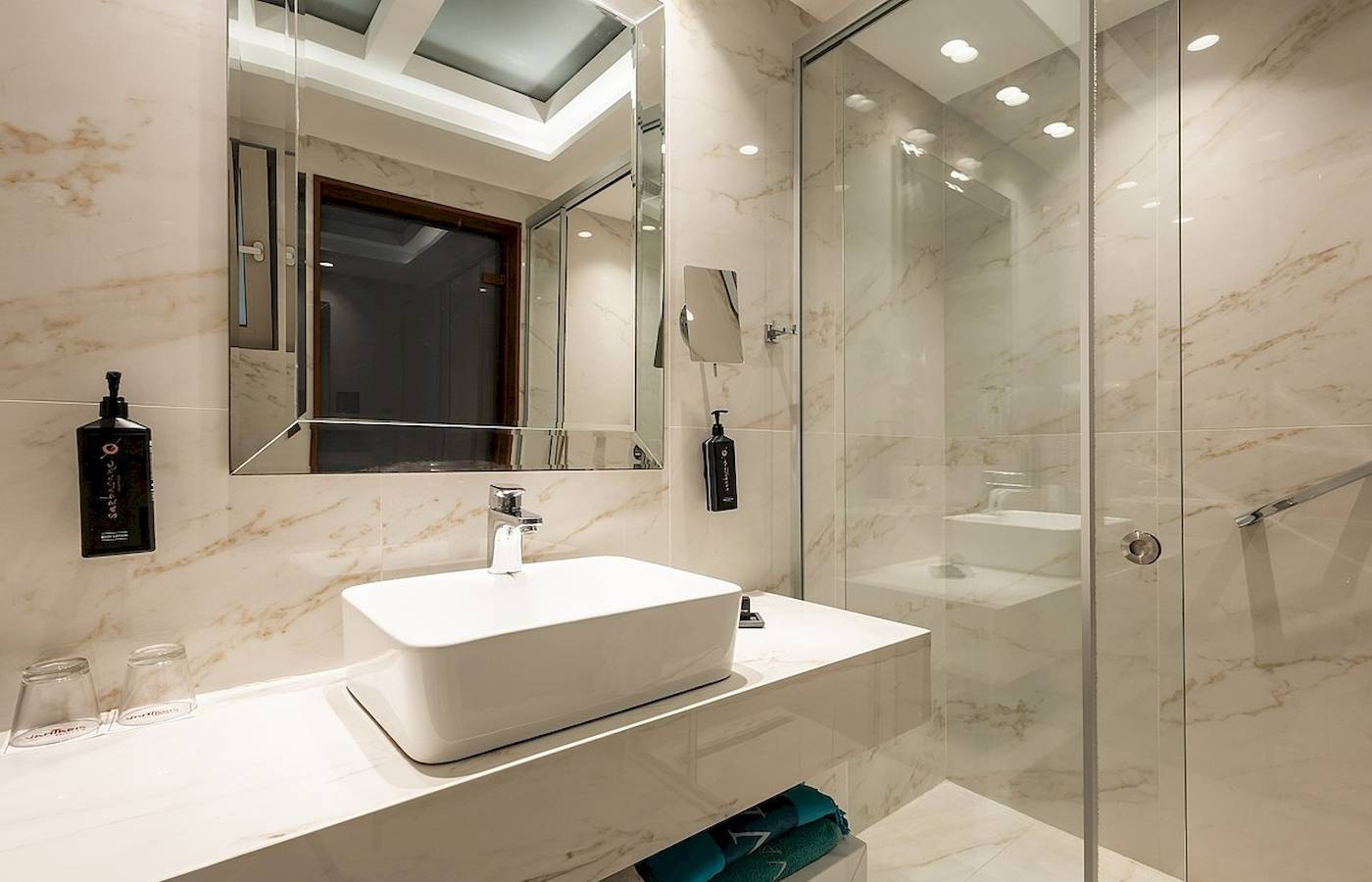 Das Badezimmer im Vantaris Palace mit weißem Waschbecken und Spiegeln.