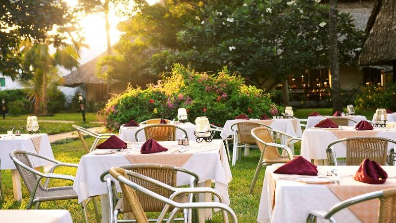 Außenrestaurant des Southern Palms Beach Resort mit gedeckten Tischen und Stühle in einer grünen Umgebung.