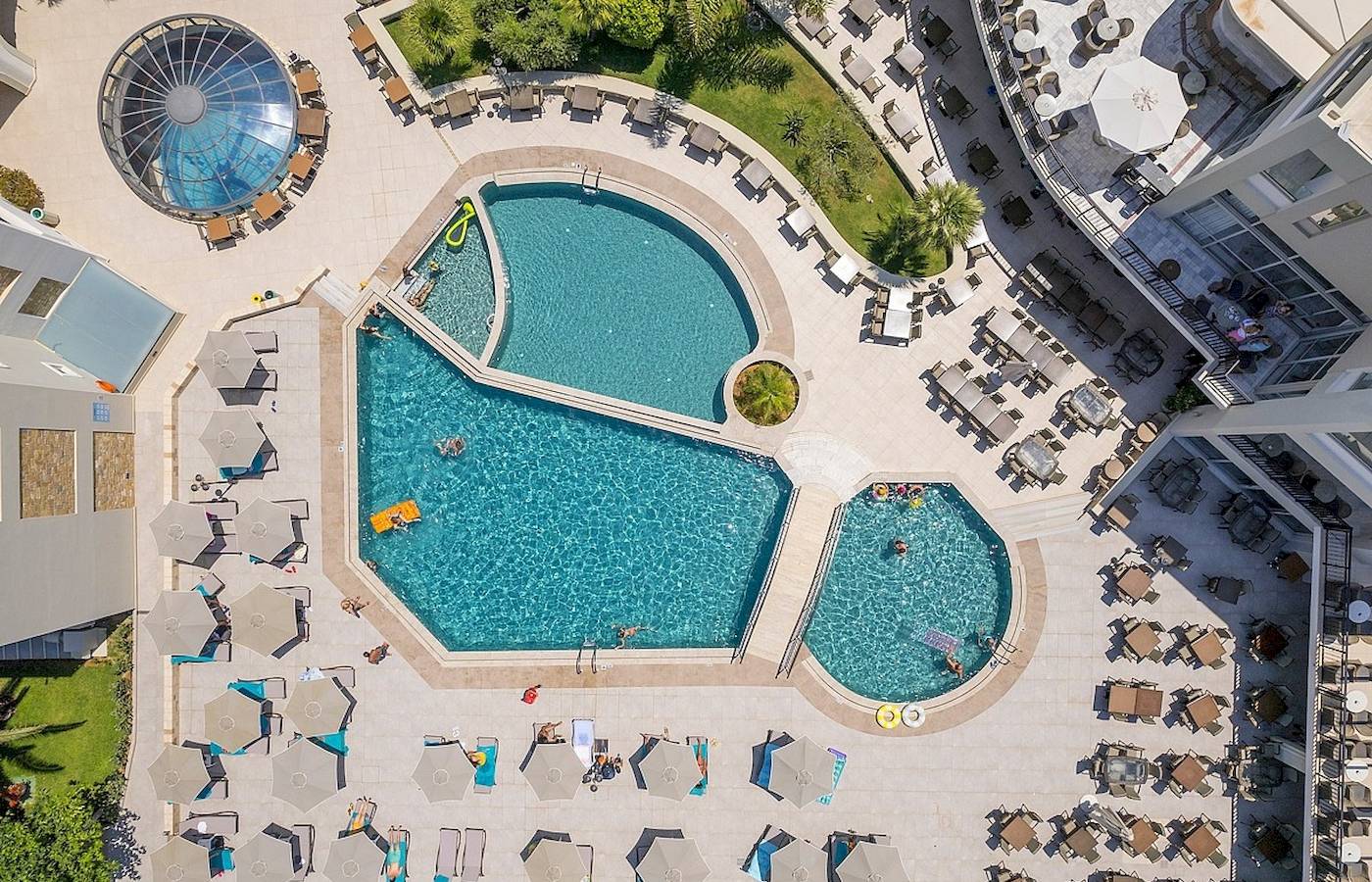 Luftaufnahme des Vantaris Palace mit Swimmingpools, Sonnenliegen und Schirmen.